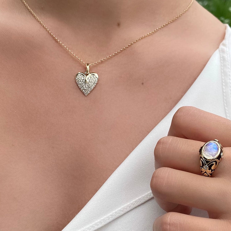 Model wearing diamond heart pendant and moonstone with enamel ring