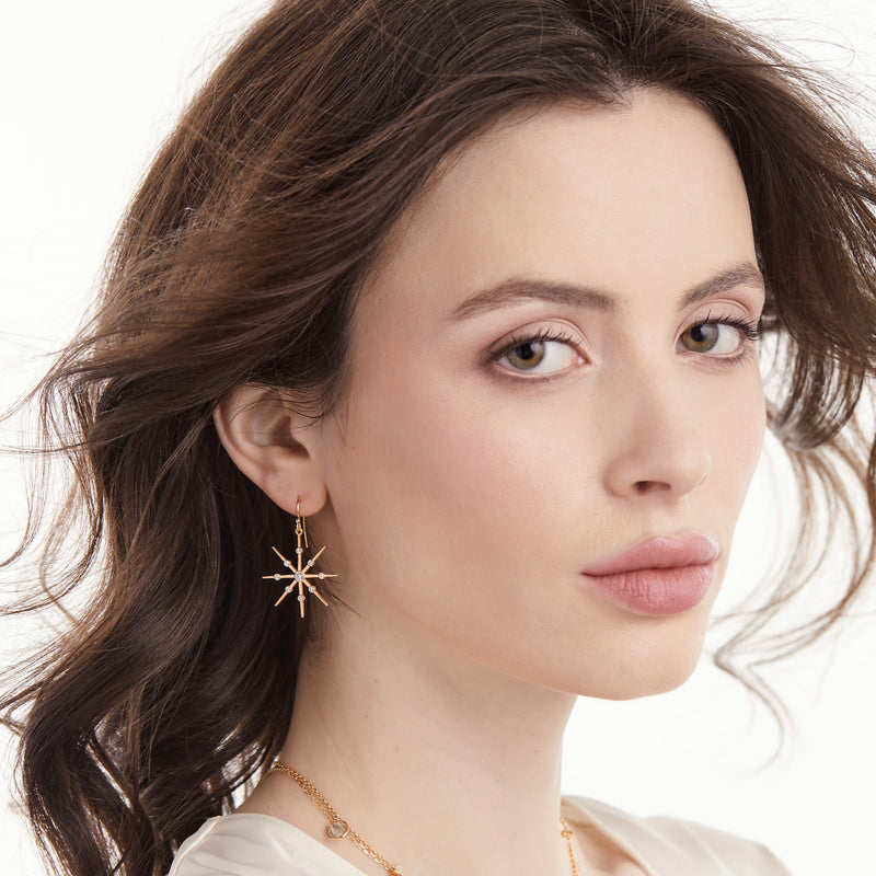 Model wearing 14k gold star and diamond earrings