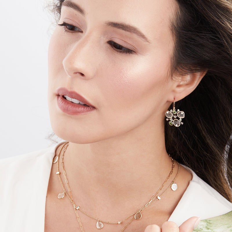 Model wearing diamond slice earrings with green sapphires