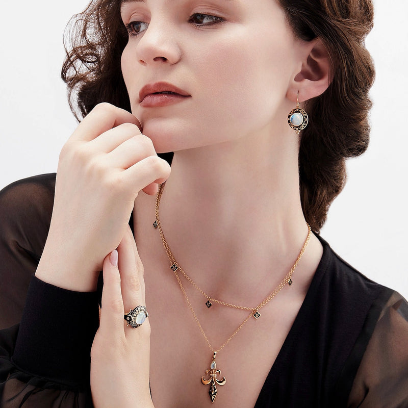 Model wearing black enamel and moonstone sword pendant necklace with moonstone and black enamel earrings and ring