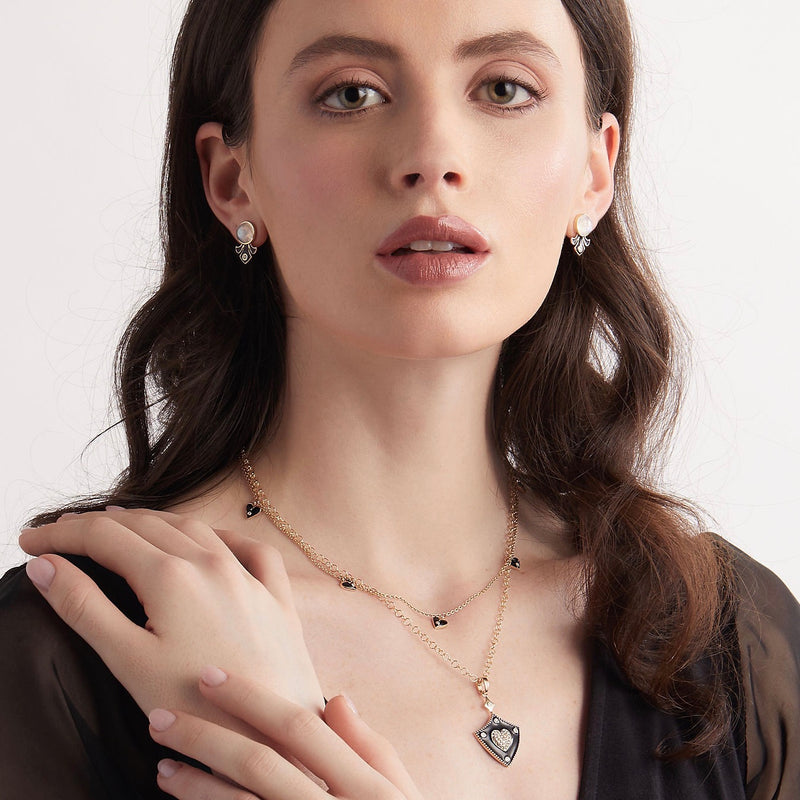 Model wearing moonstone and enamel stud earrings with matching black enamel necklaces