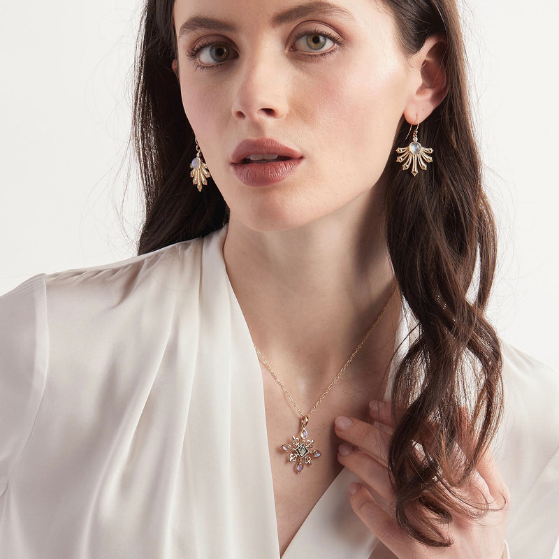 Model wearing moonstone and enamel fleur de lis pendant