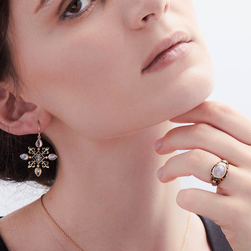 Model wearing moonstone and black enamel 14K gold scrolled ring