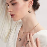 Model wearing enamel and gold  fleur de lis sword earrings